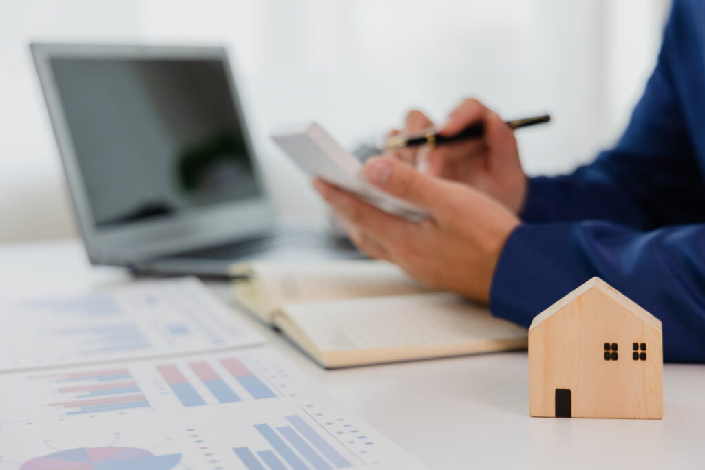 Man in a suit doing property tax calculations using a calculator of a house model