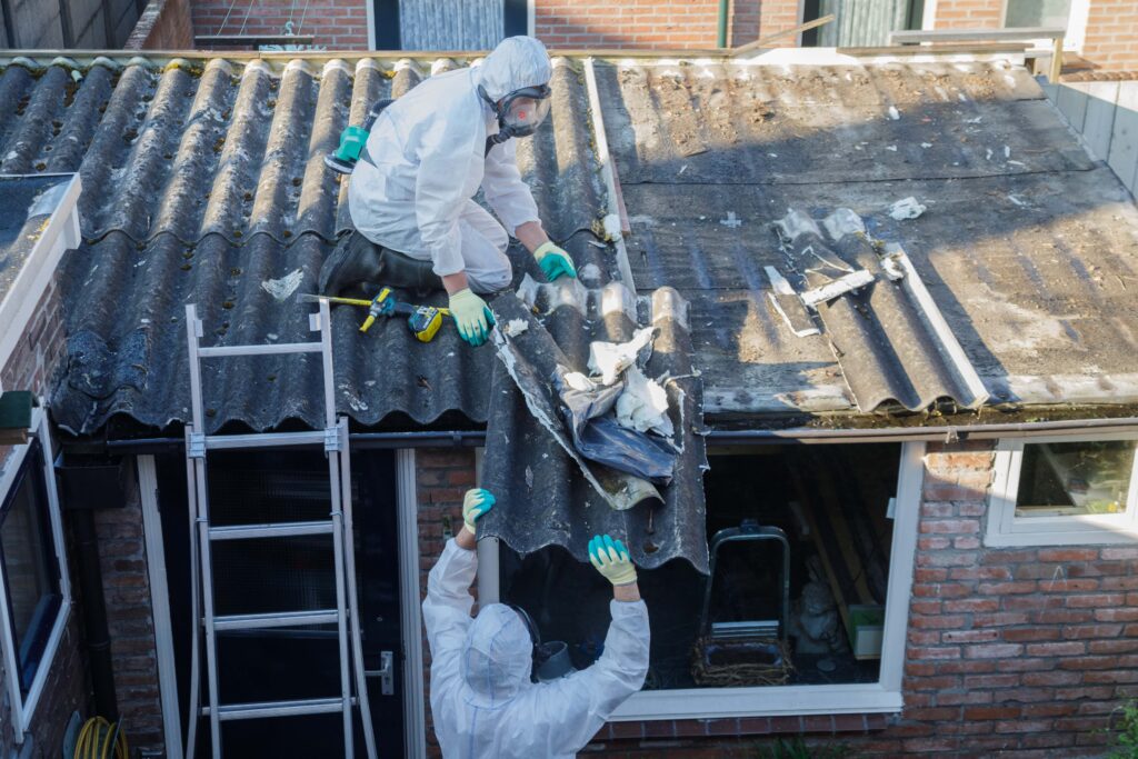 Professional asbestos removal. Man in protective suite removes asbestos roofing.