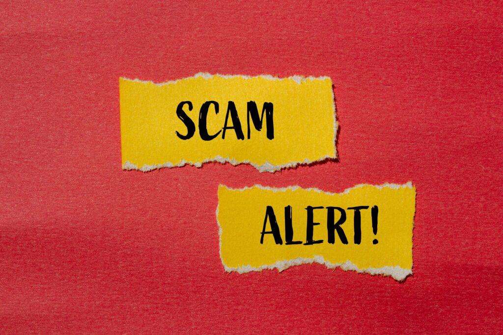 Scam alert words written on ripped yellow paper pieces with red background. Conceptual scam alert symbol. Copy space.