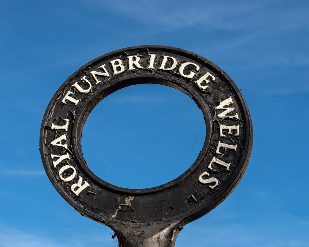 ROYAL TUNBRIDGE WELLS, KENT, UK - SEPTEMBER 15, 2019: Old circular Town sign viewed against blue sky